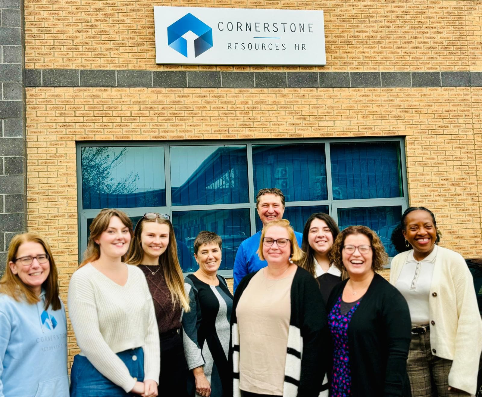 Cornerstone Resources team photo outside new office with signage